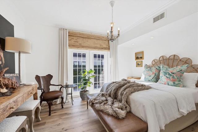 bedroom featuring french doors, crown molding, an inviting chandelier, light hardwood / wood-style flooring, and access to outside