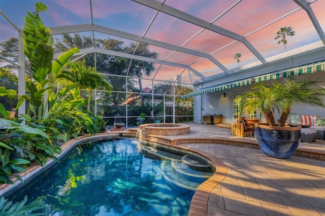 pool at dusk featuring an in ground hot tub, a lanai, and a patio