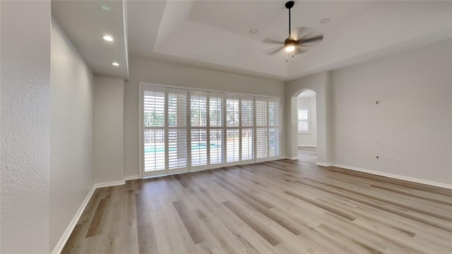 spare room featuring ceiling fan, light hardwood / wood-style floors, and a tray ceiling