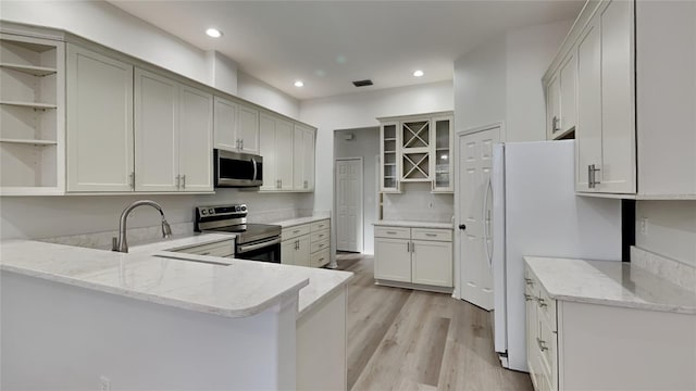 kitchen with sink, light stone counters, appliances with stainless steel finishes, kitchen peninsula, and white cabinets