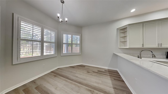 unfurnished dining area with an inviting chandelier and light wood-type flooring