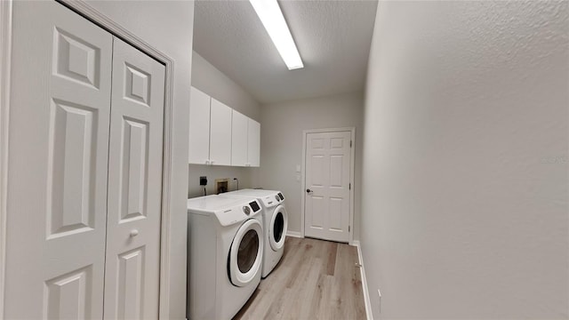 washroom featuring independent washer and dryer, cabinets, a textured ceiling, and light wood-type flooring