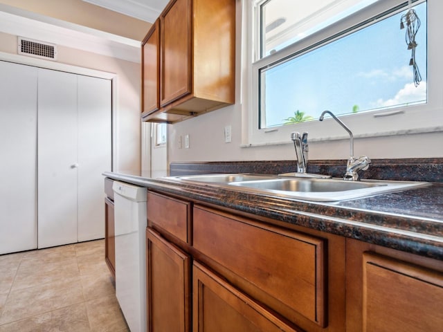 kitchen featuring white dishwasher, sink, and light tile patterned flooring