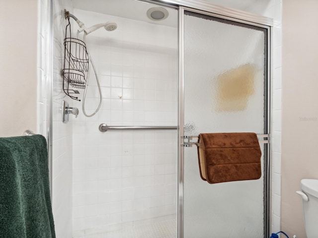 bathroom with a shower with shower door and toilet