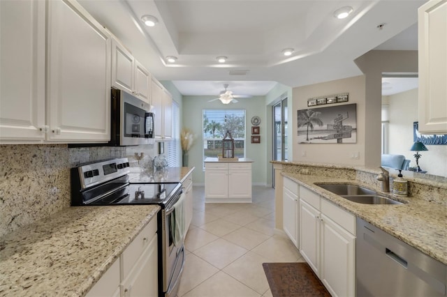 kitchen with stainless steel appliances, a raised ceiling, sink, and white cabinets