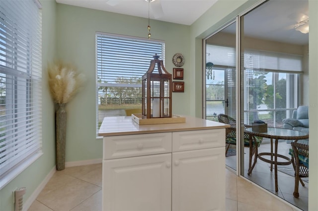 interior space featuring light tile patterned floors, plenty of natural light, white cabinets, and a kitchen island