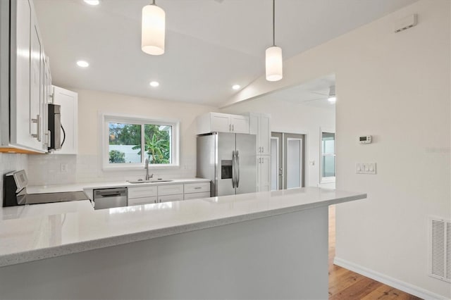 kitchen featuring white cabinetry, hanging light fixtures, kitchen peninsula, and appliances with stainless steel finishes