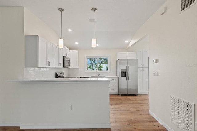 kitchen featuring appliances with stainless steel finishes, pendant lighting, white cabinets, and kitchen peninsula