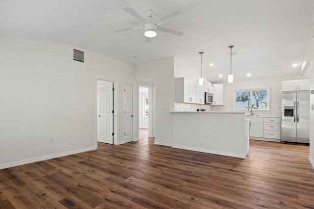 kitchen with vaulted ceiling, white cabinetry, kitchen peninsula, stainless steel appliances, and dark wood-type flooring