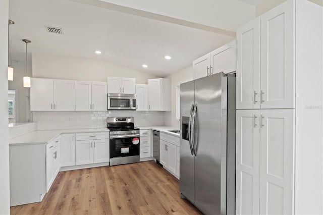 kitchen with stainless steel appliances, pendant lighting, white cabinets, and backsplash