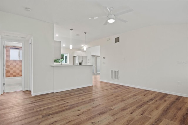 unfurnished living room with ceiling fan, wood-type flooring, and a healthy amount of sunlight