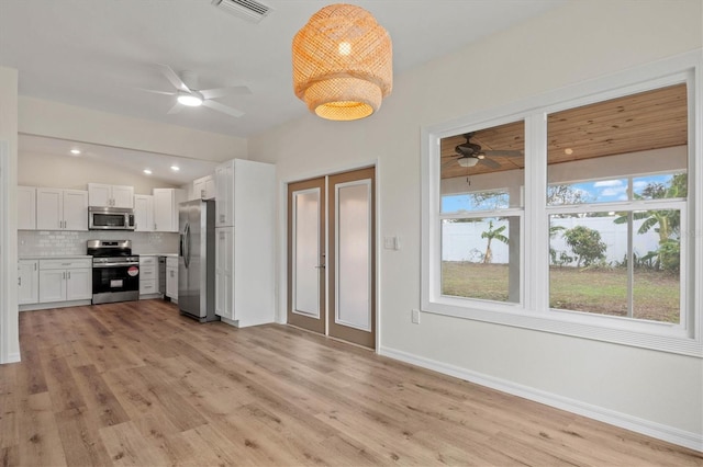 kitchen with white cabinetry, stainless steel appliances, decorative backsplash, vaulted ceiling, and light wood-type flooring