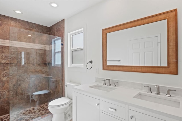 bathroom with vanity, tiled shower, and toilet