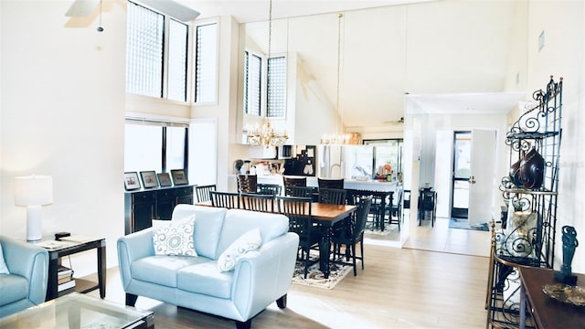 living room with hardwood / wood-style floors, a towering ceiling, and ceiling fan with notable chandelier