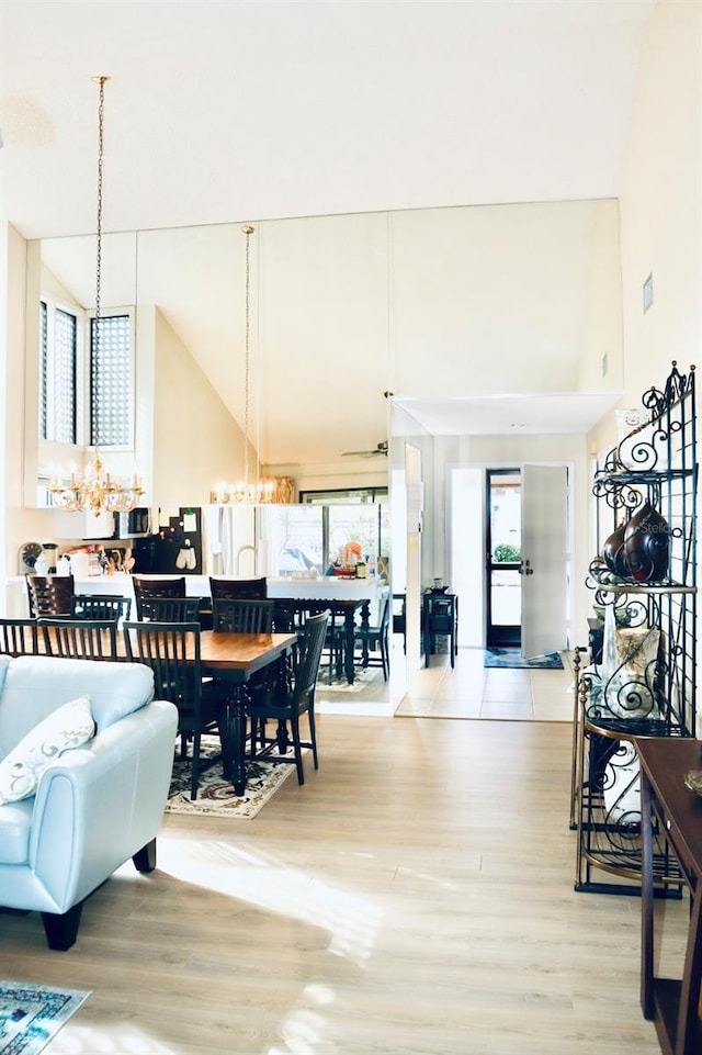 dining space with a notable chandelier, light hardwood / wood-style floors, and a high ceiling