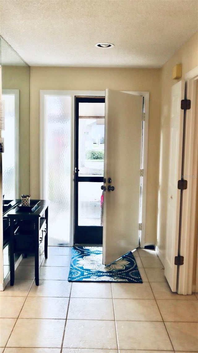 entryway with a textured ceiling and light tile patterned floors