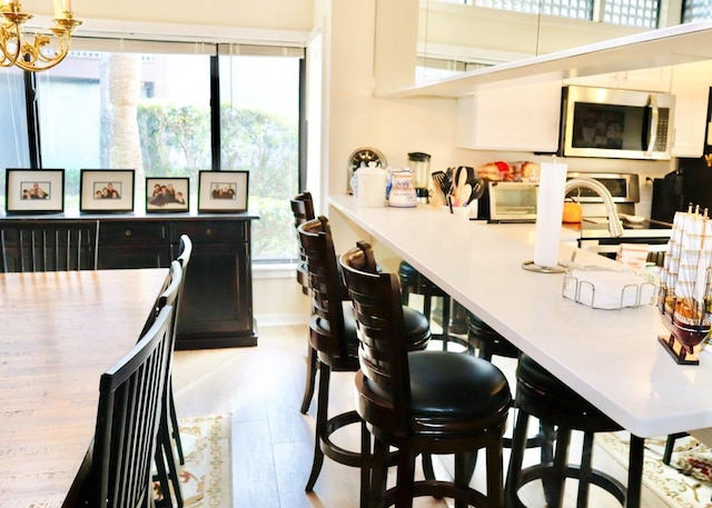 kitchen with light hardwood / wood-style floors, a breakfast bar area, and white cabinets