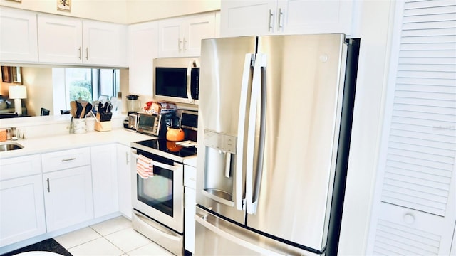 kitchen with stainless steel appliances, white cabinetry, and light tile patterned floors