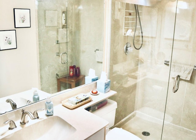 bathroom featuring vanity, a shower with door, and toilet