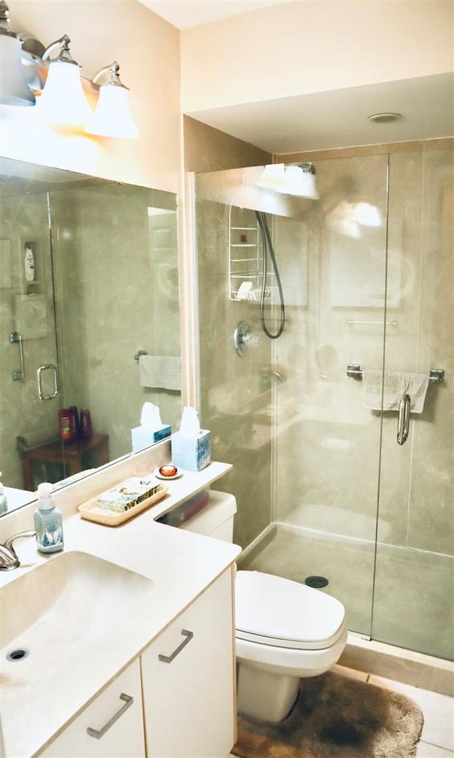 bathroom with vanity, a shower with shower door, tile patterned floors, and toilet