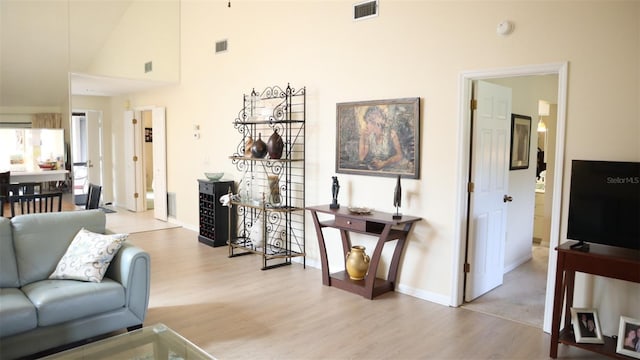 living room featuring a towering ceiling and light hardwood / wood-style flooring