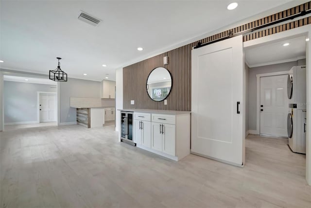 kitchen with pendant lighting, wine cooler, stacked washer / drying machine, light hardwood / wood-style floors, and white cabinets