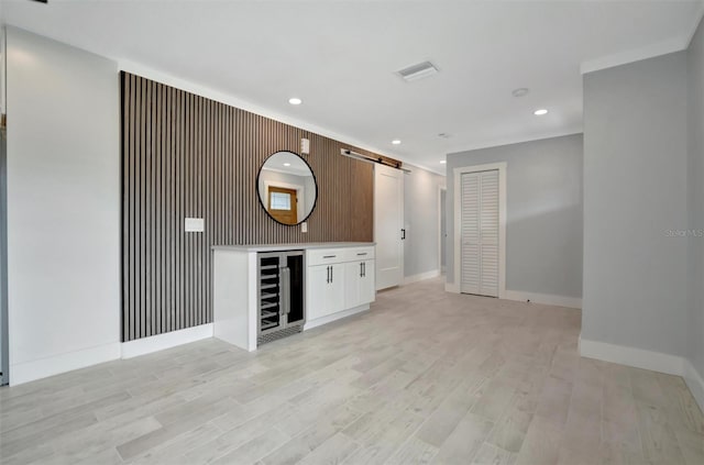 bar featuring white cabinetry, beverage cooler, a barn door, and light wood-type flooring