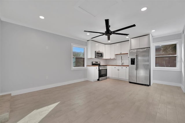 kitchen featuring light hardwood / wood-style flooring, ceiling fan, appliances with stainless steel finishes, backsplash, and white cabinets