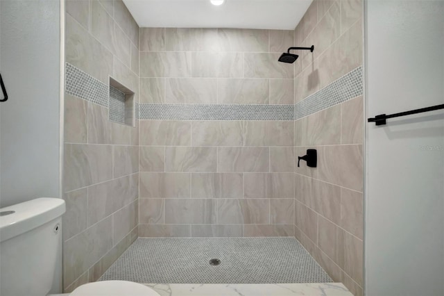 bathroom with tiled shower and toilet