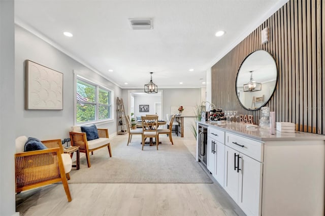 bar area featuring beverage cooler, light wood-style flooring, recessed lighting, pendant lighting, and crown molding