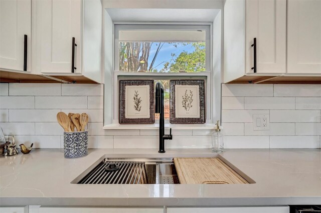 kitchen view of tasteful backsplash, light countertops, and white cabinetry