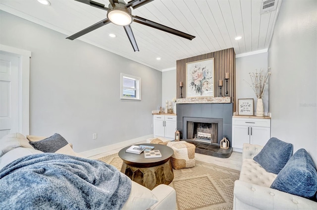 living room featuring a ceiling fan, recessed lighting, a fireplace, crown molding, and baseboards
