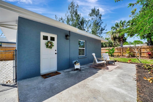 property entrance featuring a patio, fence, and stucco siding