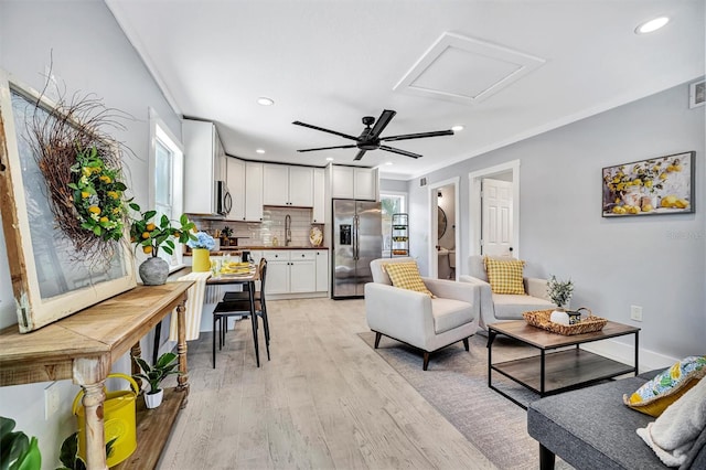 living area featuring recessed lighting, light wood-style floors, a ceiling fan, ornamental molding, and attic access