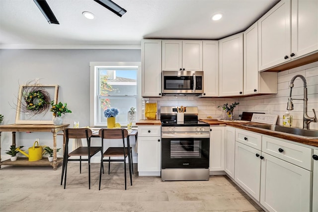 kitchen featuring stainless steel appliances, a sink, backsplash, recessed lighting, and white cabinetry