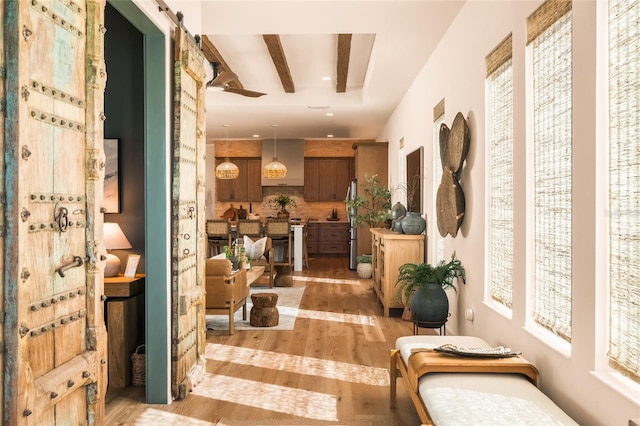 corridor featuring a barn door, light wood-type flooring, beam ceiling, and recessed lighting