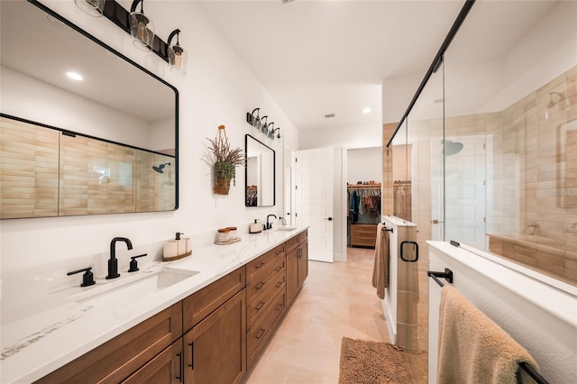 full bath with a stall shower, a sink, a spacious closet, and double vanity