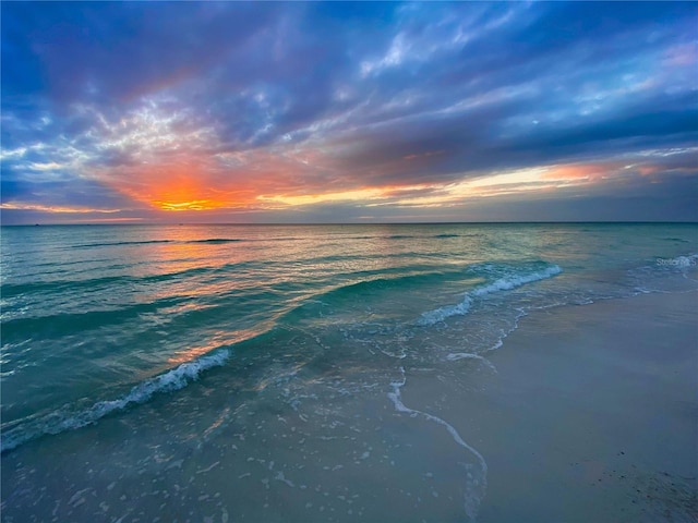 aerial view at dusk with a water view and a view of the beach