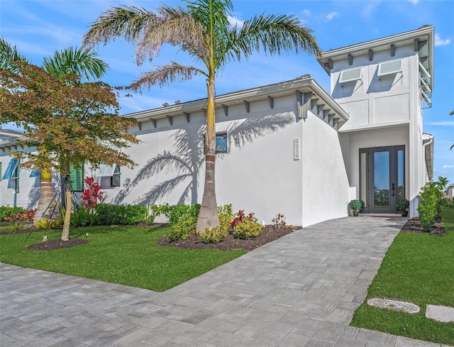 view of front of home featuring stucco siding, french doors, and a front lawn