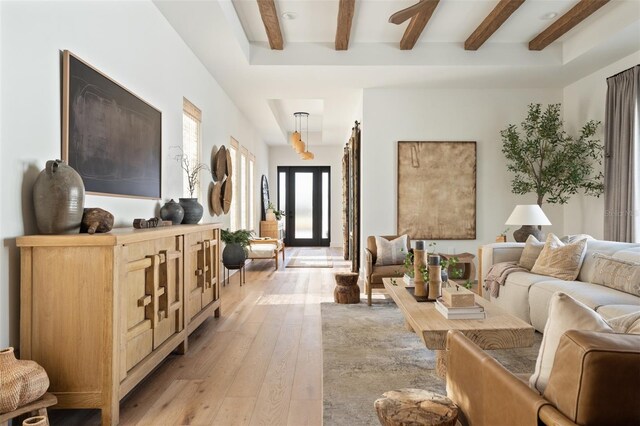 living area featuring light wood finished floors and beamed ceiling