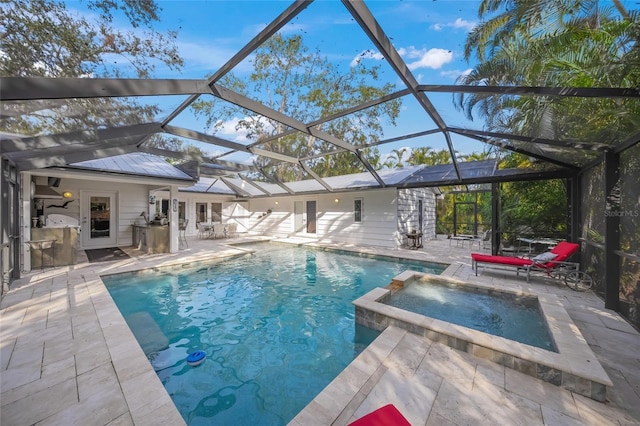 view of pool with an in ground hot tub, a patio, glass enclosure, and an outbuilding