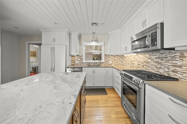 kitchen featuring white cabinetry, hanging light fixtures, light stone counters, and appliances with stainless steel finishes