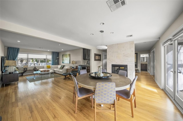 dining space with a multi sided fireplace and light wood-type flooring