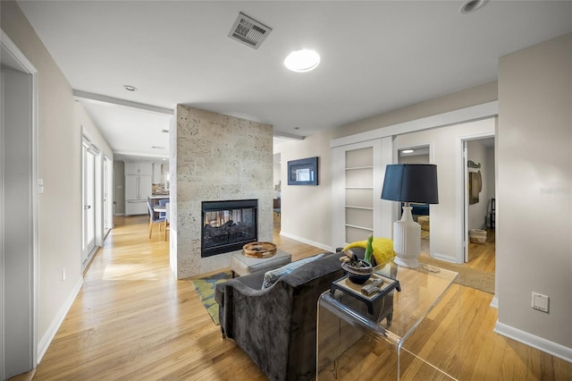 living room featuring a tile fireplace and light wood-type flooring