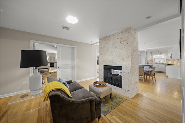 living room featuring a multi sided fireplace and light hardwood / wood-style floors