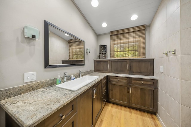 bathroom featuring vanity, wood-type flooring, and tile walls