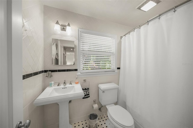 bathroom with tile walls, a shower with curtain, and toilet