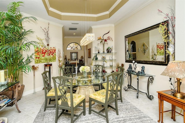 tiled dining area with ornamental molding and a tray ceiling