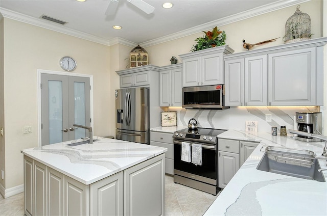 kitchen featuring light stone countertops, appliances with stainless steel finishes, a kitchen island with sink, and sink