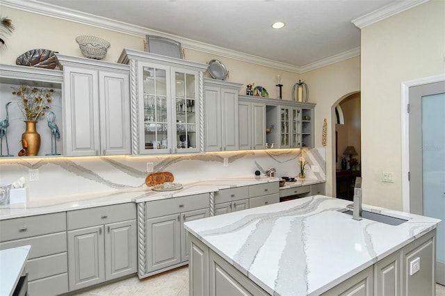 kitchen with gray cabinets, crown molding, light stone countertops, and light tile patterned floors